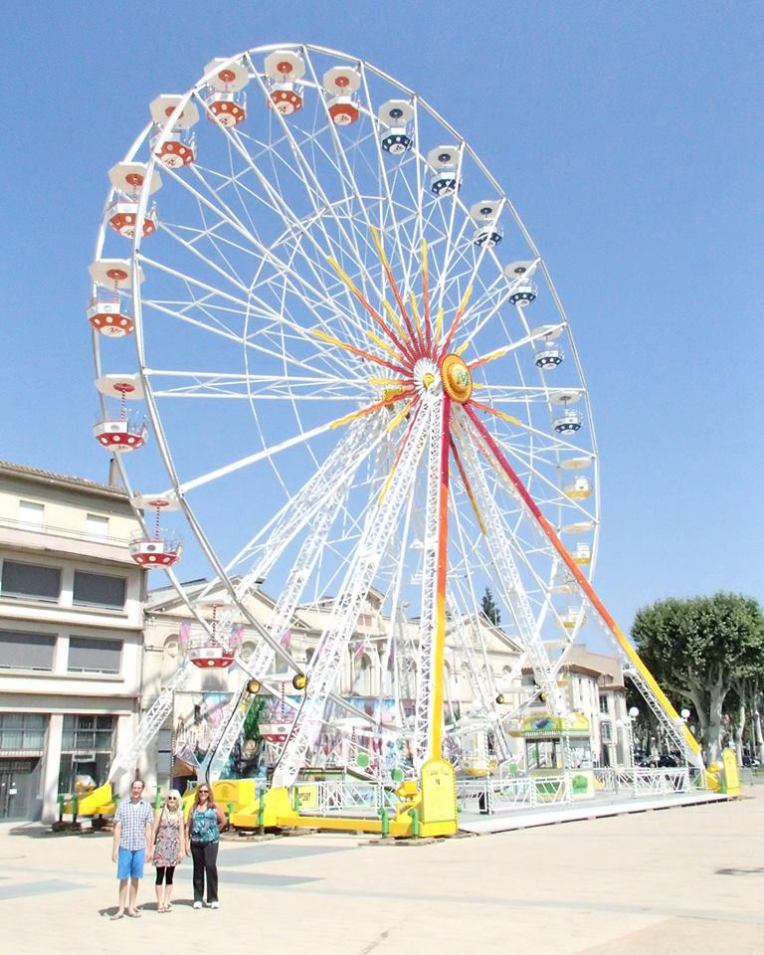 Adam, Liz, and Tracy with the Ferris Wheel set up in Square Gambetta for Festival de Carcassonne.