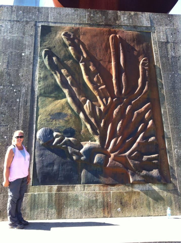 Tracy near panel of Camino routes shaped like a hand at Monte do Gozo, Hill of Joy