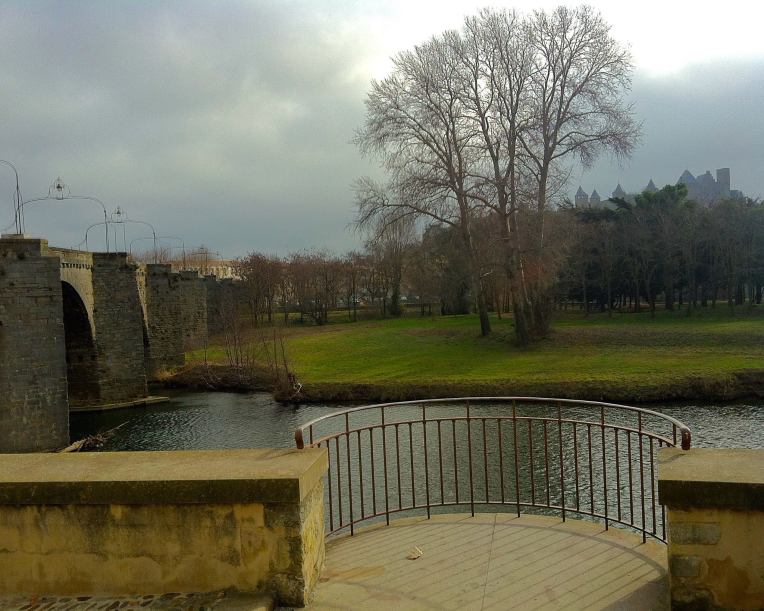 The Pont Vieux (Old Bridge) on the left, the balcony next to the Chapelle Notre Dame de la Sante overlooking the River Aude, and the medieval Cité de Carcassonne on the hill above.